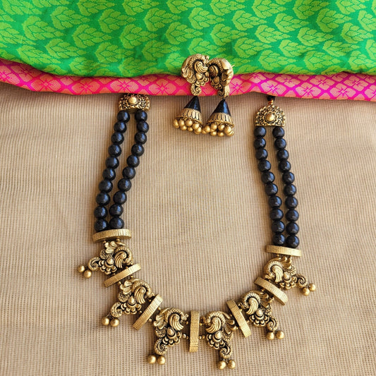 Antique gold peacock motif terracotta pendant close-up