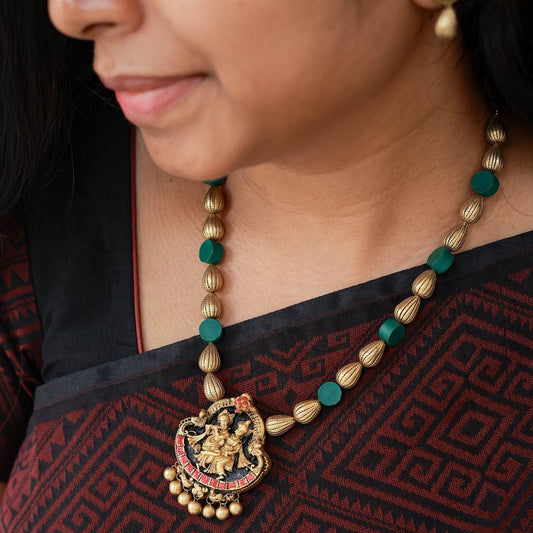 Mavinai - Rain drop lined antique gold bead and dark green disk bead with Radha Krishna pendant with pink highlights terracotta jewellery with matching peacock stud