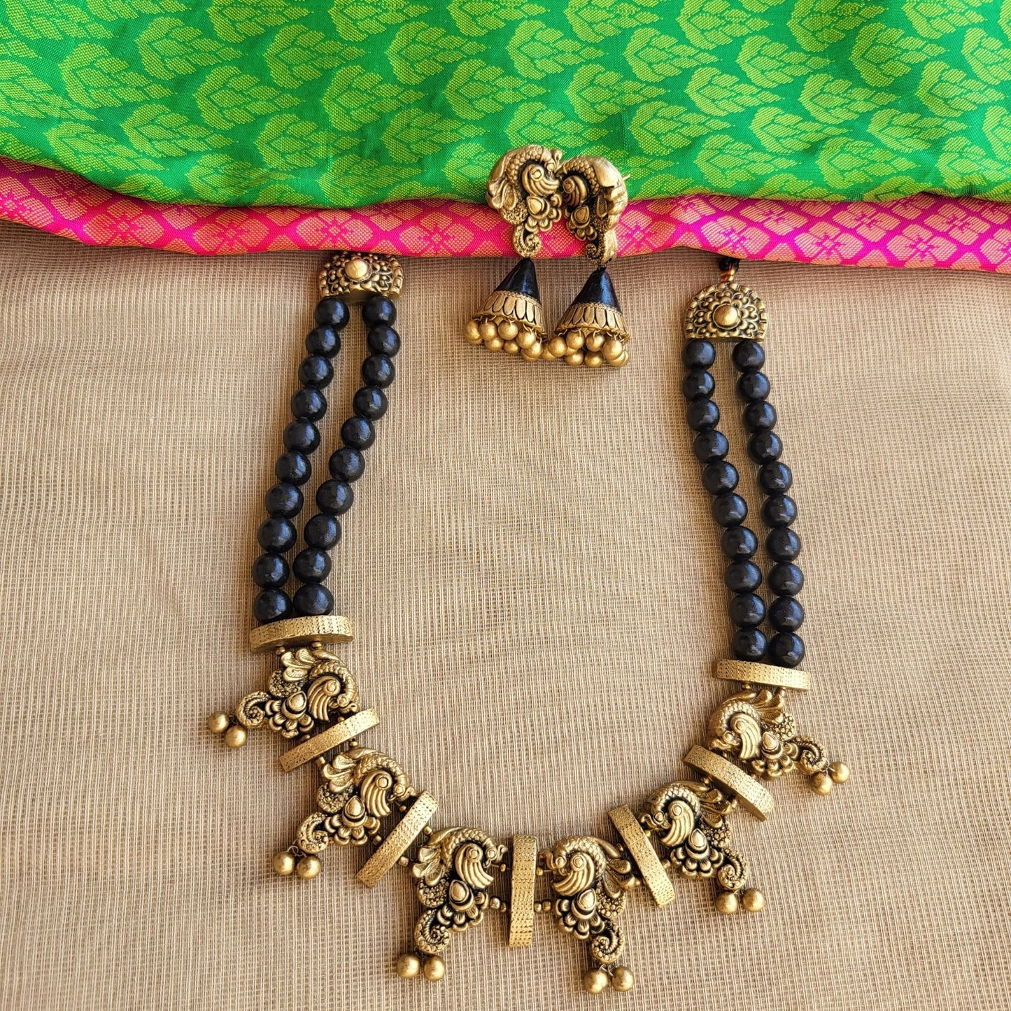 Antique gold peacock motif terracotta pendant close-up